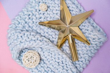 Close up of Christmas tree toys in the shape of a golden star and white balls on blue cozy scarf. Xmas and New Year celebrating party.