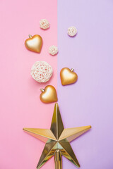 Christmas tree toys in the shape of a golden star, balls and hearts on pink and violet background. Xmas and New Year celebrating party. Flat lay, minimalism