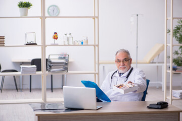 Old male doctor working in the clinic