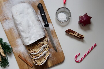Flat lay of Christmas bread with candy cane, cinnamon and candle on white background