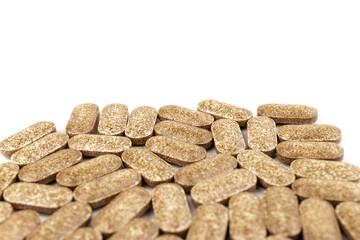 Nutrition supplements, brown vitamin pills on white background.