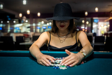 Sexy woman playing poker in elegant black dress at clubhouse.