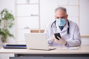 Old male doctor working in the clinic