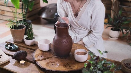 Cacao ceremony in atmospheric space with green plants and candles. Woman making ritual healthy drink from cocoa beans