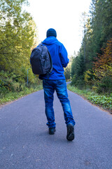 Man with a backpack walks on a forest road
