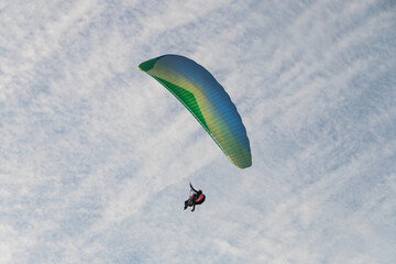 paraglider soars in the sky against the background of the sky and white clouds