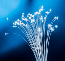 Fototapeta premium Bundle of optical fibers with lights in the ends. Blue background.