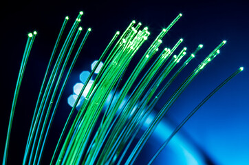 Bundle of optical fibers with green light. Blue background.