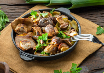 Cooked porcini mushrooms in the frying pan on the wooden table.
