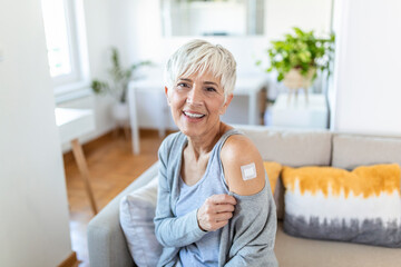 Mature woman with adhesive bandage on her arm after Corona virus vaccine. First aid. Medical,...