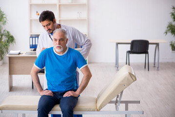 Fototapeta premium Old male patient visiting young male doctor