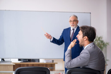 Old businessman and young male employee in front of whiteboard