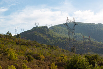 High voltage electricity poles installed on opposite slopes of a deep valley. High voltage poles with high voltage wires not yet connected.