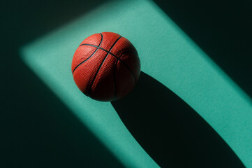 Brown new basketball ball with natural lighting on green background. Sport team concept. Horizontal sport theme poster, greeting cards, headers, website and app