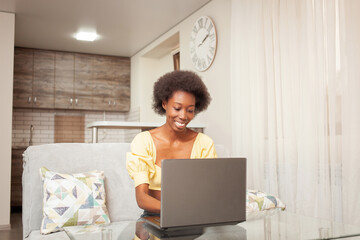 a African American woman freelancer, work from home. woman in front of laptop is happy, smiling. Winning lottery, hired, stocks have risen, cryptocurrency has grown, good news.