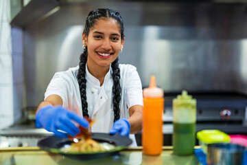 Smiling kitchen trainee food styling in restaurant