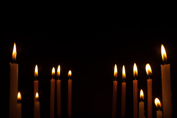 Group of candles with beautiful bright yellow golden flames on black background. Ideas for Halloween, Christmas, Home, Romance, Love, Copy space for you