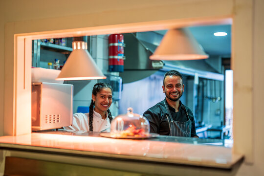 Smiling chef and trainee in commercial kitchen at restaurant