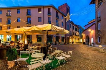 Outdoor restaurant on small town square in the evening in Alba, Italy.