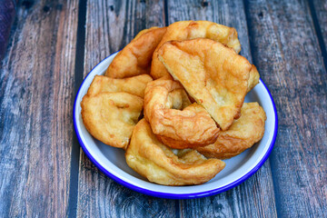 Traditional Bulgarian home made deep fried  patties  covered with sugar  оn rustic backgroud.Mekitsa or Mekica,  on wooden  rustic  background. Made of kneaded dough that is deep fried 