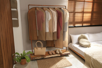 Obraz na płótnie Canvas Garment bags with clothes hanging on rack in bedroom
