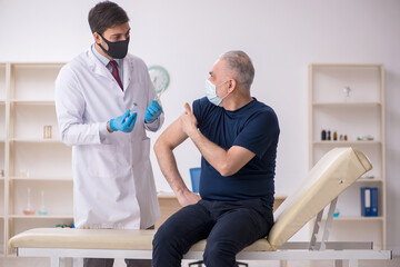 Obraz premium Old male patient visiting young male doctor in vaccination conce