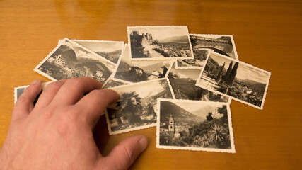 antique photos of past memories of the city of merano, south tyrol, italy, are chosen by the hands of a caucasian man