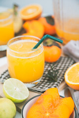 persimmon juice in a glass And there are orange slices and a blender all around.