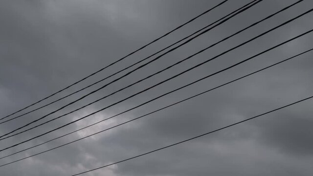 Wires against the sky are swaying from the wind.