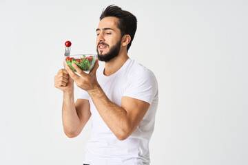 a man in a white t-shirt in a plate with salad a snack healthy food