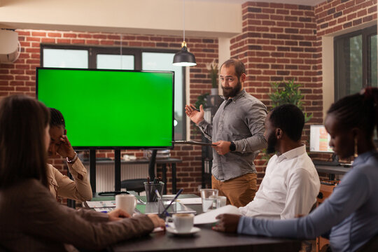 Entrepreneur man standing in front of mock up green screen chroma key monitor with isolated display explaining partnership strategy working in startup office. Concept of businesspeople at work