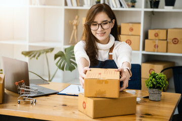 Business owner picking up parcel boxes And use a computer to check online orders to prepare the packaging. pack products to send to customers.