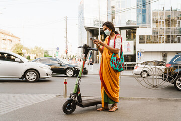 Young indian woman using cellphone while standing outdoors