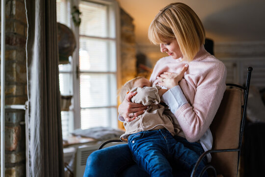 Young Mother With Disability In Wheelchair Breast Feeding Her Child At Home