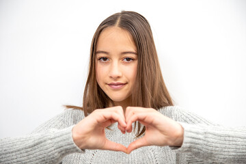 Romantic concept, young girl, over isolated background, showing heart symbol and shape with hands