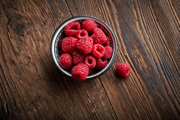 Raspberry in a ceramic bowl over wooden rustic background