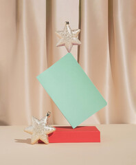 Christmas or New Year composition with golden holiday star ornaments and mint green notebook. Minimal New Year resolutions concept.