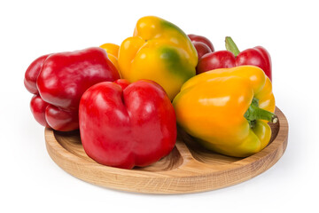 Multicolored bell peppers on wooden dish on white background