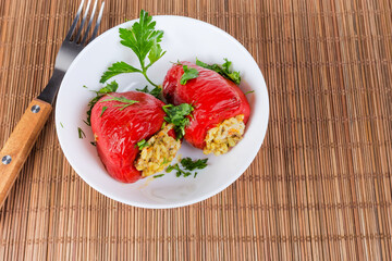 Cooked stuffed bell peppers in bowl on bamboo table mat