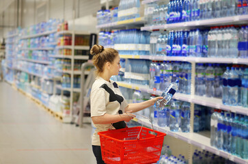 Woman choosing a dairy products at supermarket.woman choosing a bottle of water in a supermarket