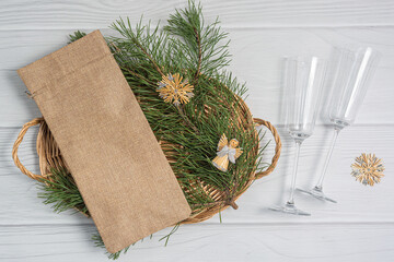 Christmas mockup beige wine bag and wine glass on wicker tray flatlay. New Years Eve Mock up