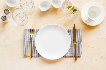 Tableware set with empty plate with dishware and glasses on napkin