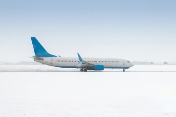 A passenger jet plane moves on the runway in a severe blizzard