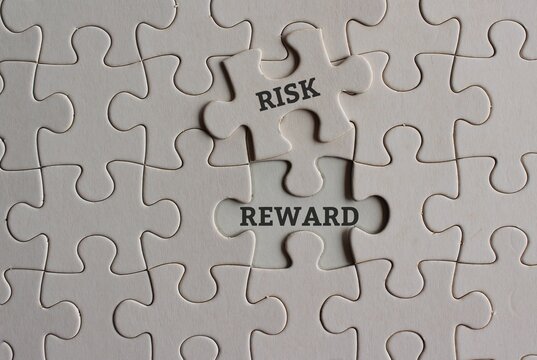 Business, risk and reward concept. Top view image of jigsaw puzzle with text RISK and REWARD.