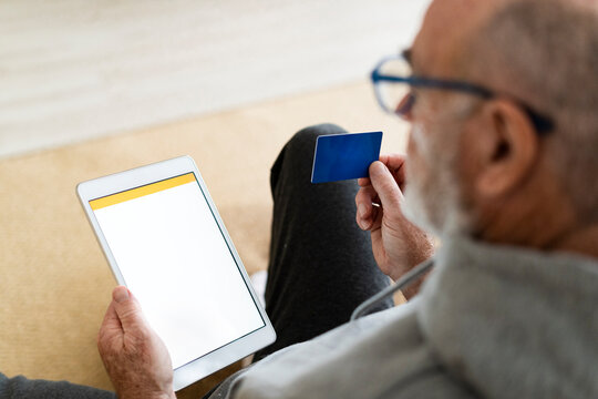 Man with credit card using tablet PC at home