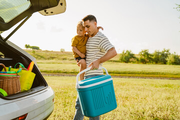 Young father holding his son and cooler bag by car trunk outdoors - Cooler Bags South Africa