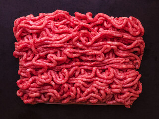 Raw minced meat briquette on a dark cement background. Top view.