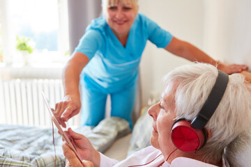 Altenpflegerin hilft Seniorin mit Kopfhörer beim Musik hören
