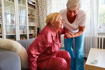 Pflegedienst Frau hilft Seniorin bei Aufstehen vom Sofa
