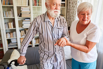 Altenpflegerin hilft Senior mit Demenz im Schlafanzug